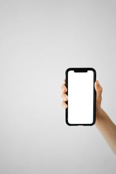 Vertical shot of a hand holding a smartphone with a blank screen, ideal for mockups.