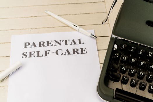 Close-up of paper with 'Parental Self-Care' beside a typewriter, pen, and clip on a wooden desk.