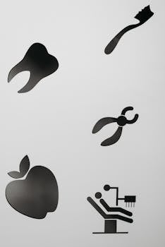 Silhouette cutouts of dental health symbols including tooth, apple, and dental chair on white background.