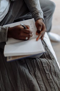 A person taking notes with a pen in a lined notebook, emphasizing focus and productivity.